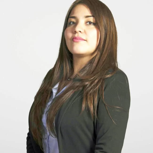 Retrato Ivonne Collin de Acerta Latam mujer joven con cabello castaño largo, vistiendo blazer negro y blusa azul claro sobre fondo blanco.