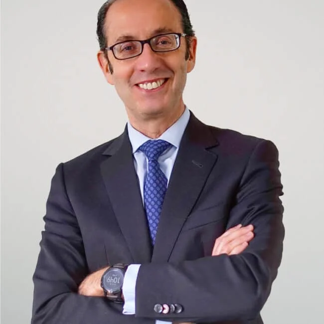Retrato de medio cuerpo de Francisco Ordoñez CEO, viste traje azul oscuro y camisa blanca, posando de brazos cruzados sobre un fondo blanco.