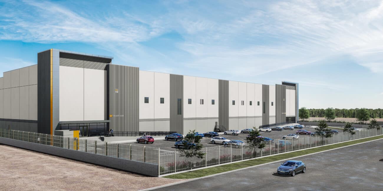Renderizado de una moderna nave industrial de gran escala con fachada en tonos grises y blancos, estacionamiento con vehículos y entorno despejado bajo un cielo azul.