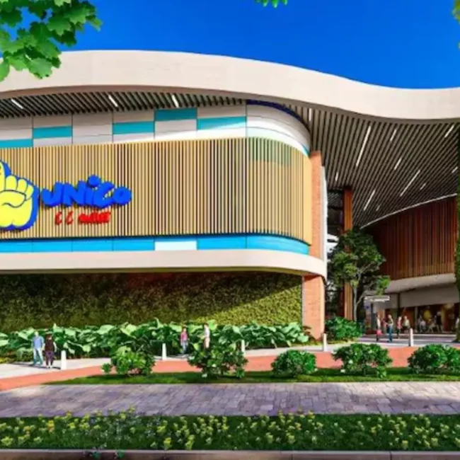 Fachada moderna del Centro Comercial Único con diseño bioclimático, muros verdes verticales y paneles de madera bajo un cielo despejado.